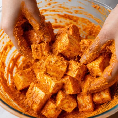 In a large bowl, mix together the olive oil, tandoori paste, grated ginger, turmeric, and a good yoghurt and stir until completely combined